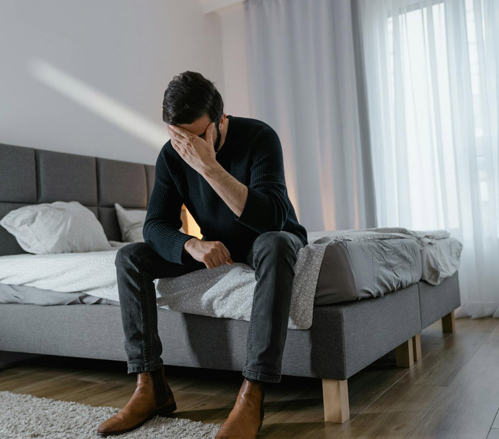 Man sitting on the bed deep in thoughts and emotions