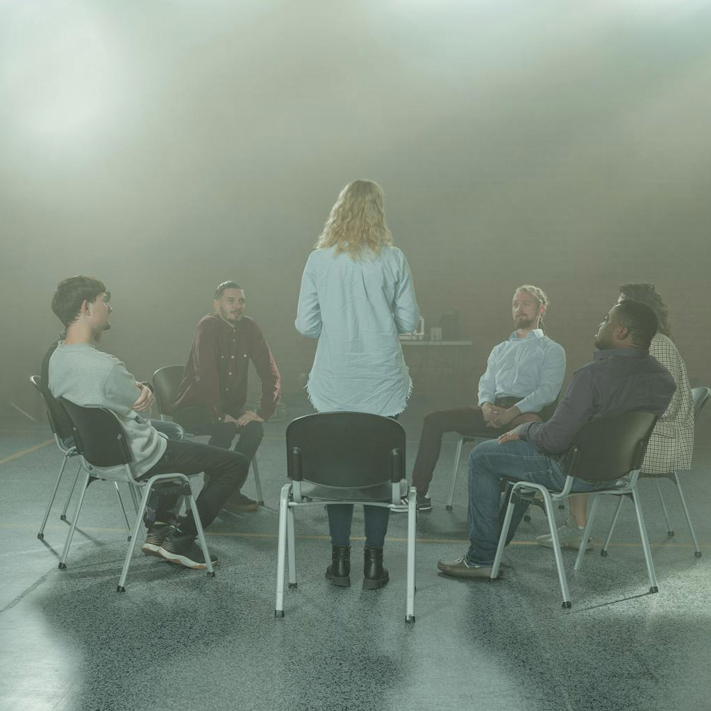 Group therapy session showing the therapist standing and addressing the group